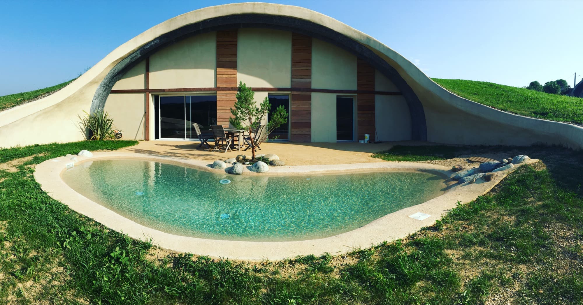 Maison enterrée à toiture végétalisée avec bassin naturel organique
